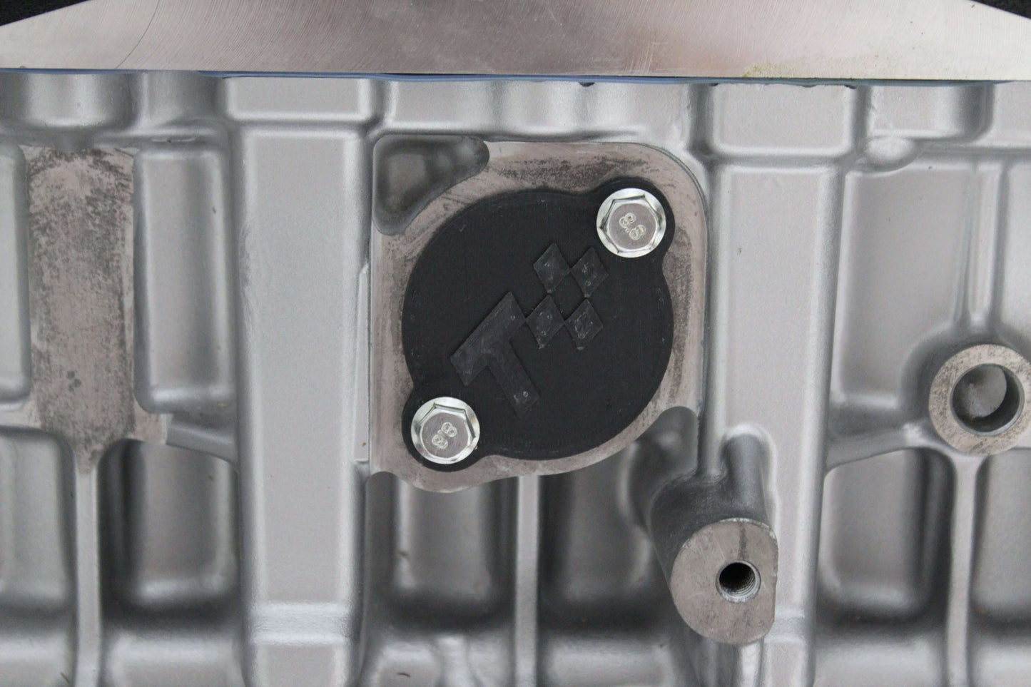 Close-up of N52 injector port cover showing bolts and engine block for maintenance and repair.